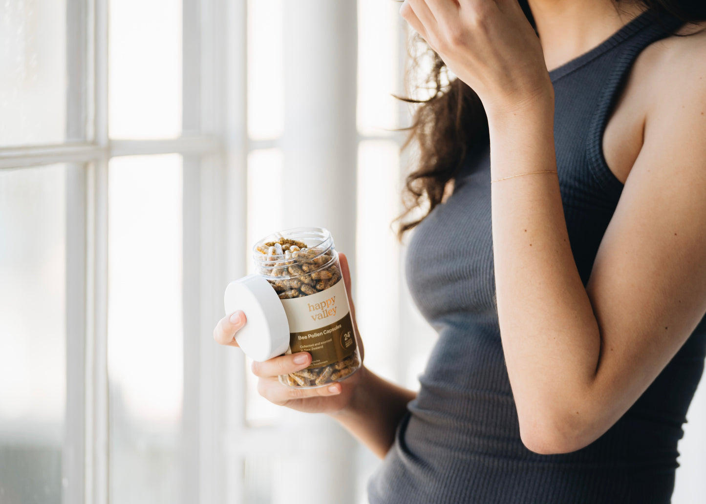Close-up of Happy Valley Honey Bee Pollen Capsules 300, showing the smooth, golden capsules in a clear container.