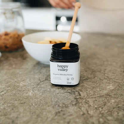 Jar of Happy Valley Honey Organic Mānuka Honey UMF® 12+ with a golden honey color and label visible.