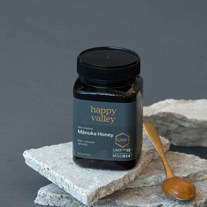 Jar of Happy Valley Honey Manuka Honey UMF® 15+ with golden honey dripping from a spoon, close-up of the honey's rich texture.