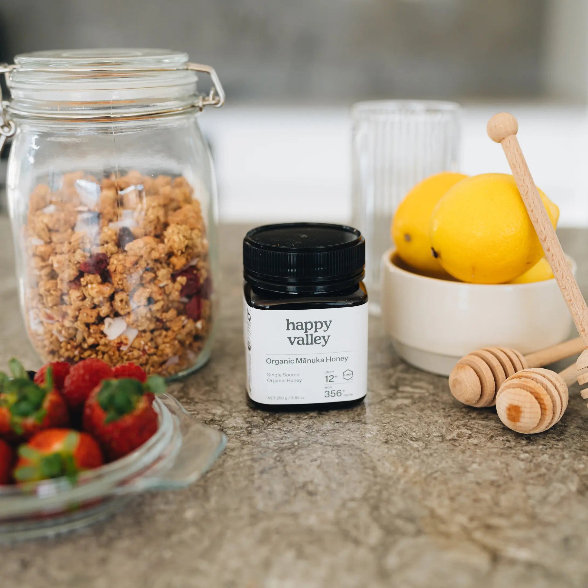 Jar of Happy Valley Honey Organic Mānuka Honey UMF® 12+ with a gold label and honey drizzling from the spoon.
