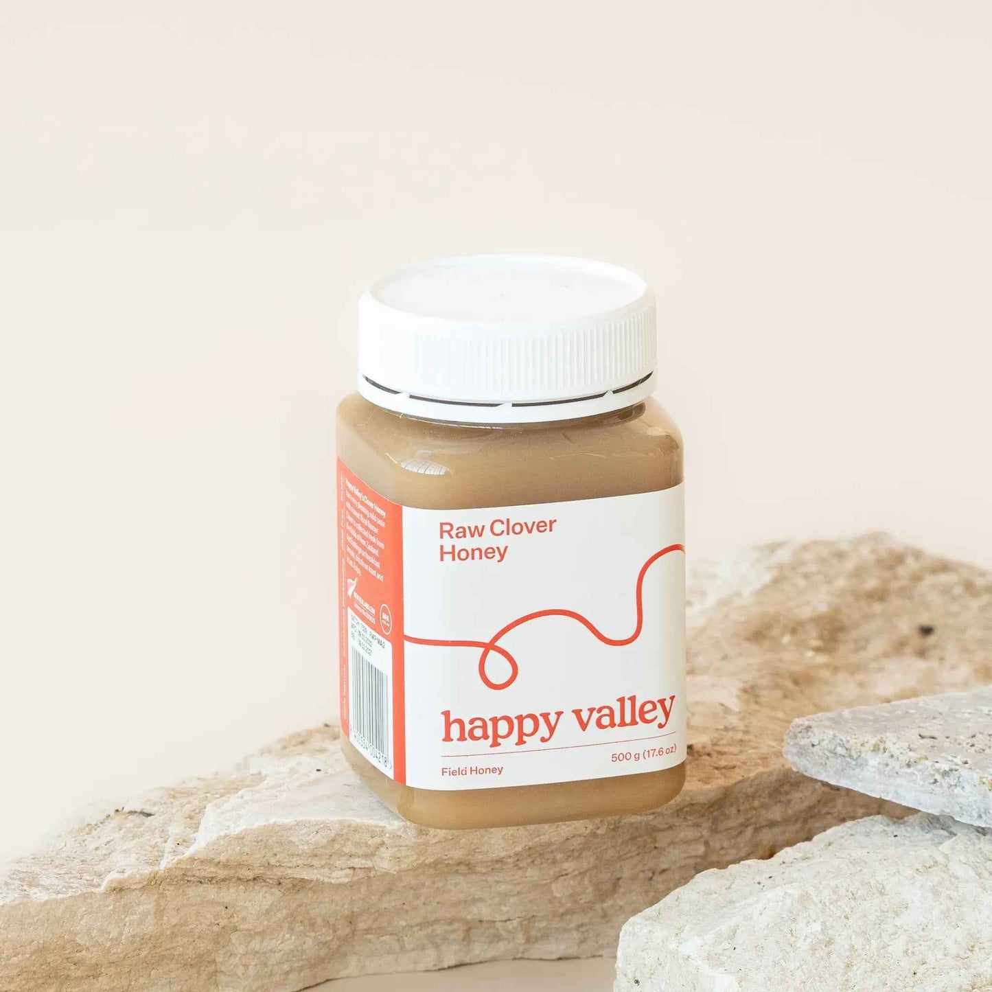 Jar of Happy Valley Honey Clover Field Gourmet & Raw Honey showing golden honey with a floral background