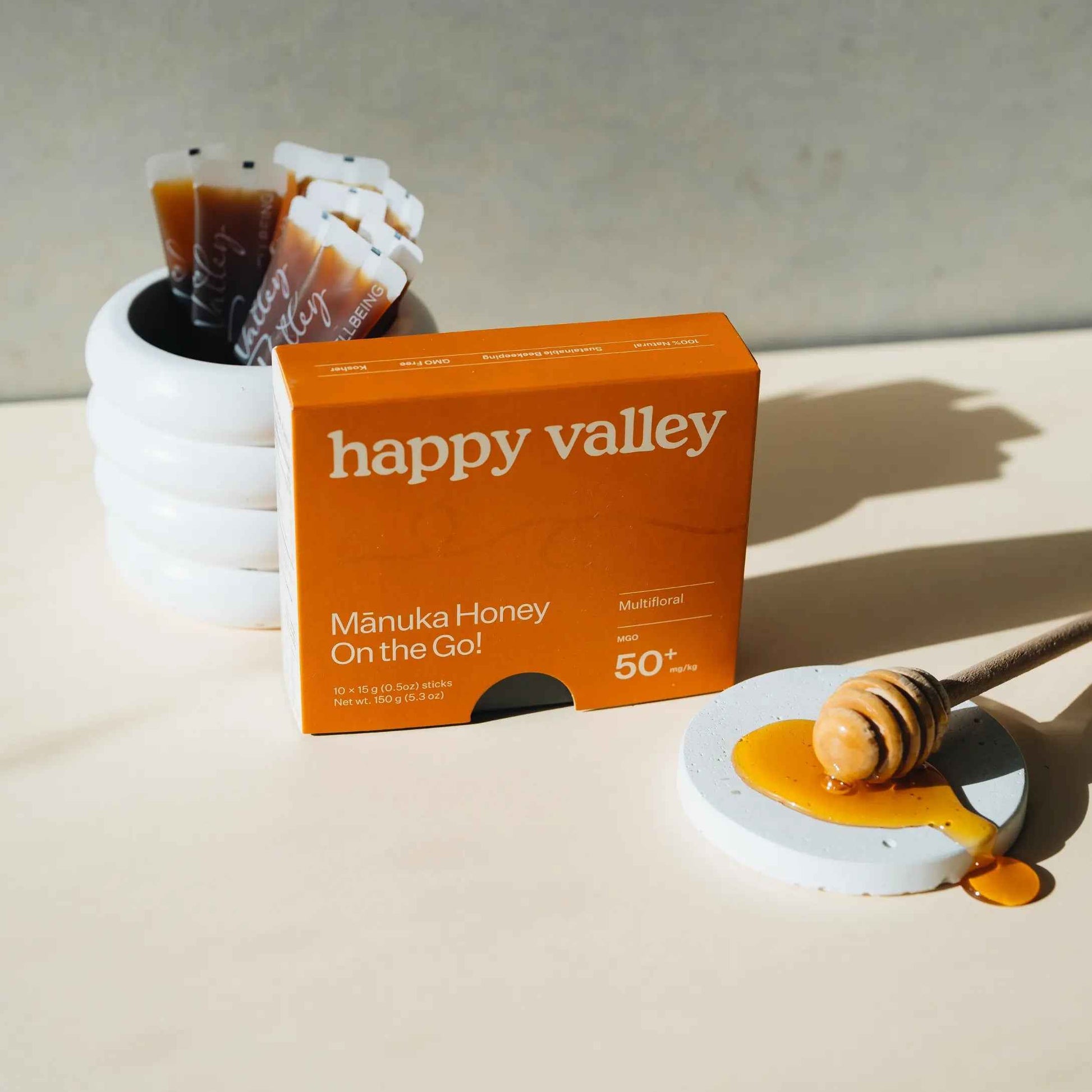 Four Happy Valley Honey Manuka honey packets with multicolored labels, each containing MGO 50+ Manuka honey sticks.