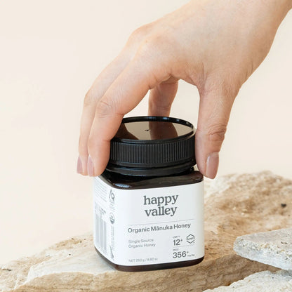 Jar of Happy Valley Honey Organic Mānuka Honey UMF 12+ with golden honey visible in the clear glass jar