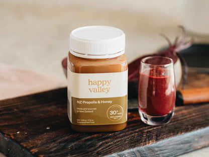 Close-up of a jar of Happy Valley Honey Propolis with honey and propolis extract visible inside.