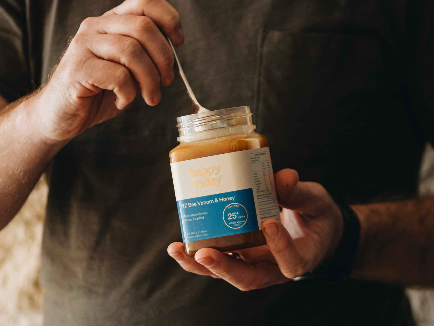 Jar of Happy Valley Honey bee venom with honey, featuring a clear label and honeycomb detail on the packaging.