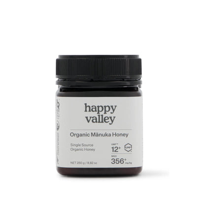 Organic Manuka Honey UMF® 12+ jar from Happy Valley Honey, showcasing golden, thick honey with a white label and wooden honey dipper