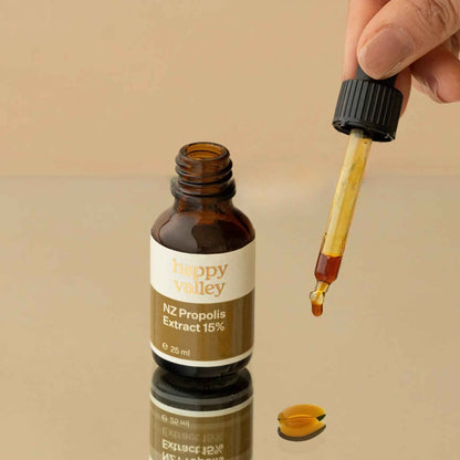 Close-up of a jar of Happy Valley Honey Propolis Extract NZ with a golden liquid and natural honeycomb background.