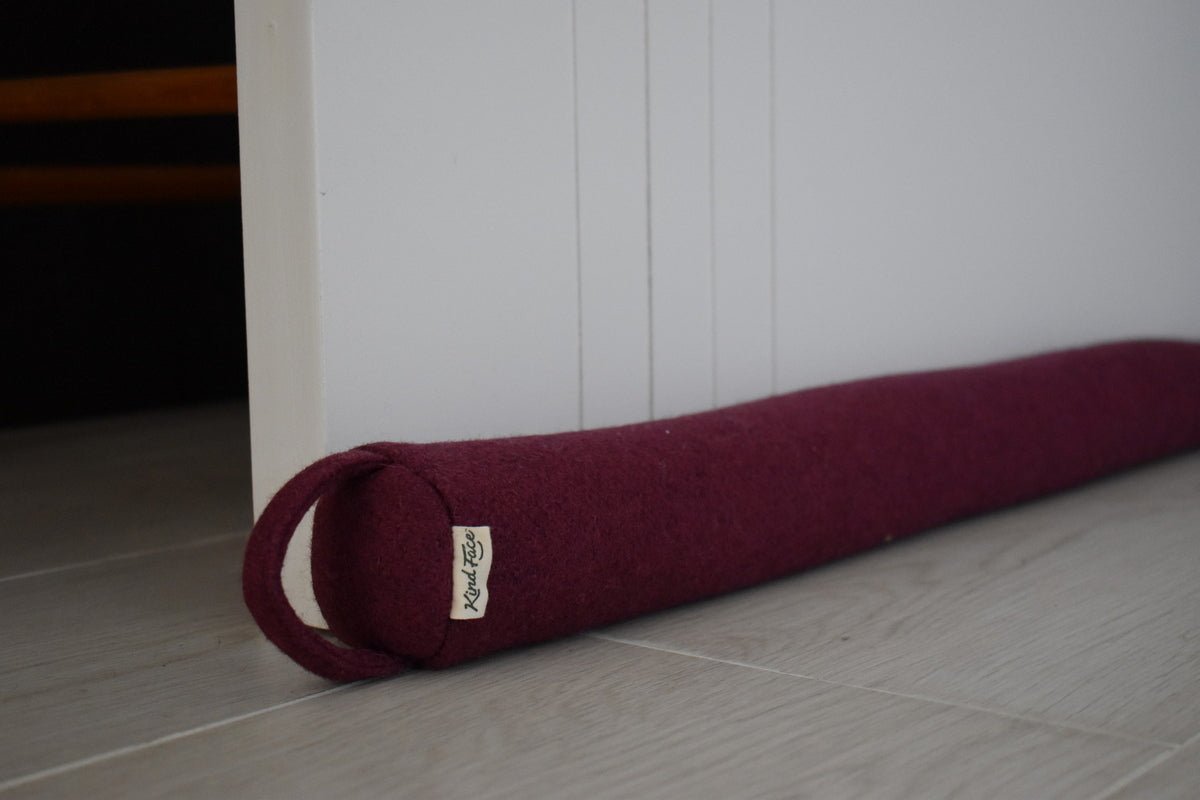 Felted NZ wool draught stopper by Do Not Disturb Sleep Company blocking a door gap to prevent drafts and improve insulation.