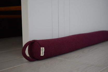 Felted NZ wool draught stopper by Do Not Disturb Sleep Company blocking a door gap to prevent drafts and improve insulation.