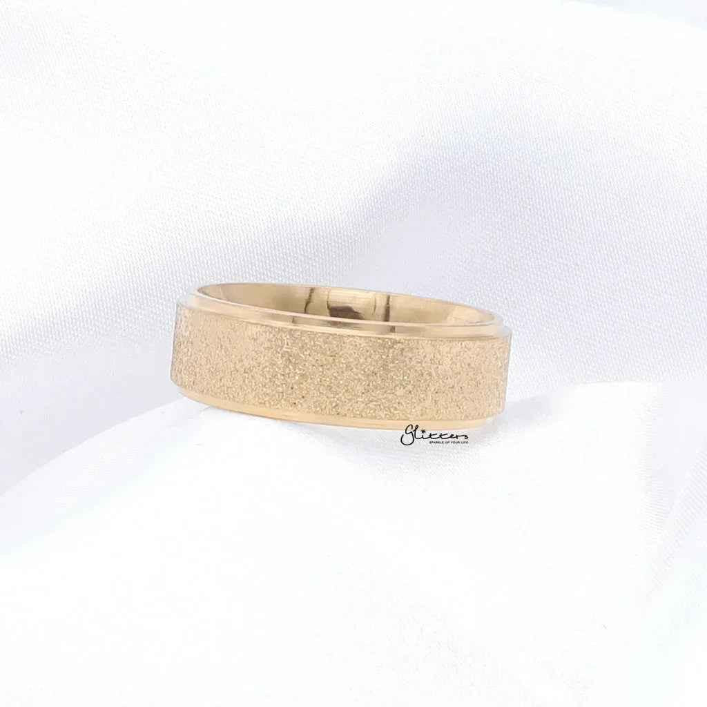 Gold stainless steel band ring with sandblasted finish, 8mm width, by Glitters, shown in close-up on a white background.
